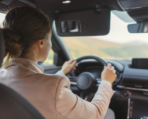 Rear view of young woman driving her electric car.